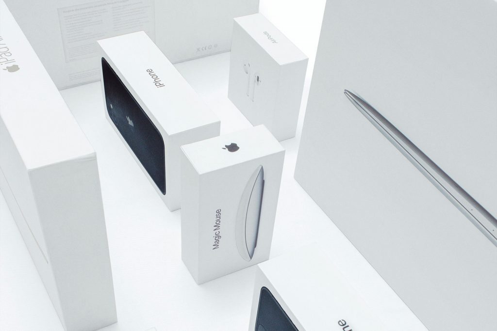 Several Apple product packagings featuring the iconic Apple logo prominently displayed on a plain background. The ample white space surrounding the logo is a distinctive brand asset, creating a clean and recognisable visual identity for Apple products.