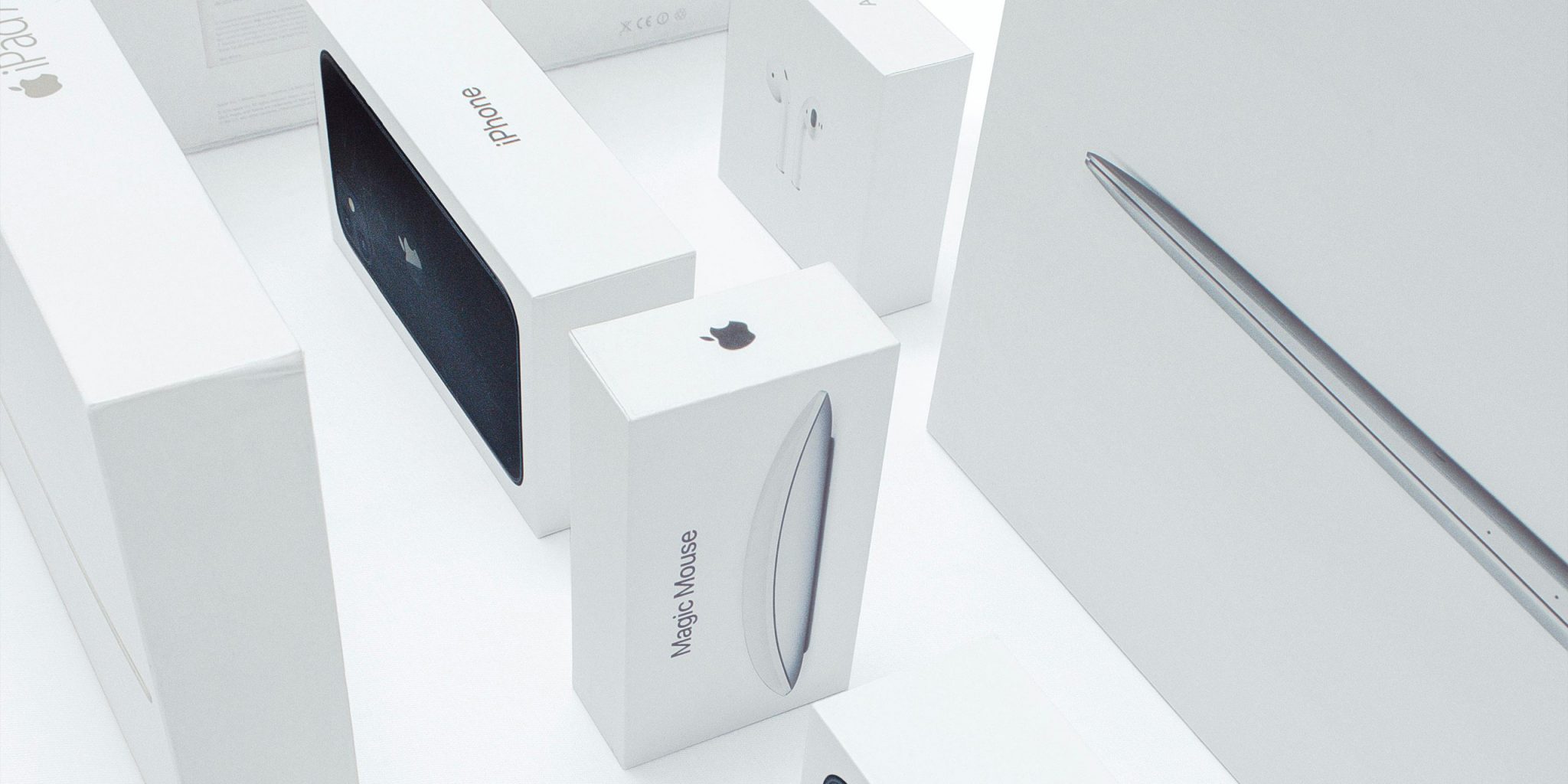 Several Apple product packagings featuring the iconic Apple logo prominently displayed on a plain background. The ample white space surrounding the logo is a distinctive brand asset, creating a clean and recognisable visual identity for Apple products.