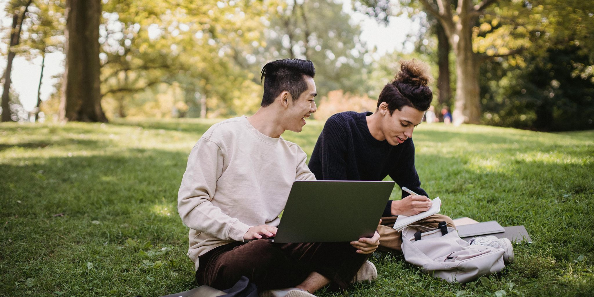 Zwei Männer sitzen in einem Park, machen ein Brainstorming und schreiben. Dieses Bild leitet einen Blogbeitrag namens „Was ist eine Tagline plus 50+ inspirierende Beispiele“ ein.