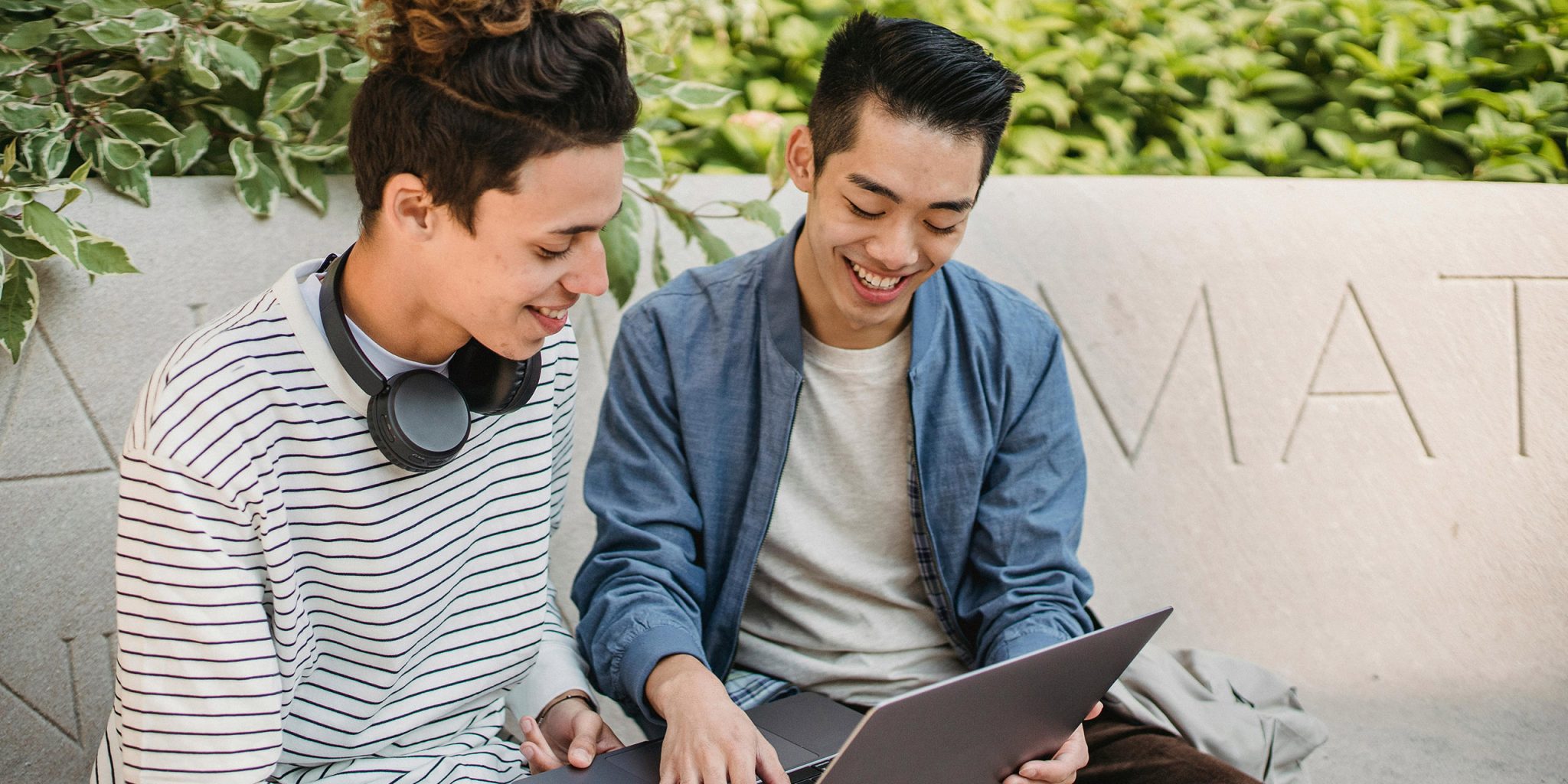 Zwei Männer arbeiten draußen an einem Laptop und sehen glücklich aus. Dies ist das Intro zu einem Artikel über Employer Branding, auch bekannt als Arbeitgeber-Branding.