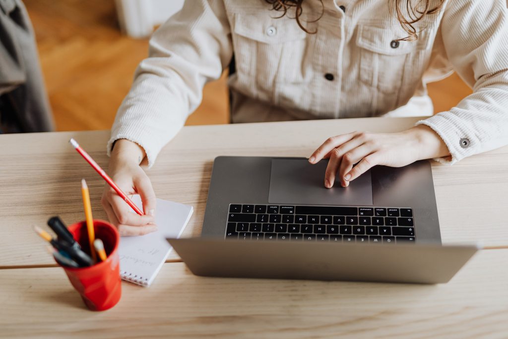 Eine Frau, die an einem Laptop und einem Notizblock arbeitet. Das ist die Einleitung zu meinem Artikel "Ein tiefgreifender Einblick ins Thema Branding".