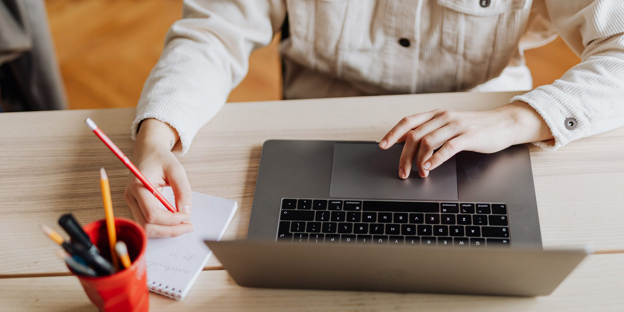 Eine Frau, die an einem Laptop und einem Notizblock arbeitet. Das ist die Einleitung zu meinem Artikel "Ein tiefgreifender Einblick ins Thema Branding".