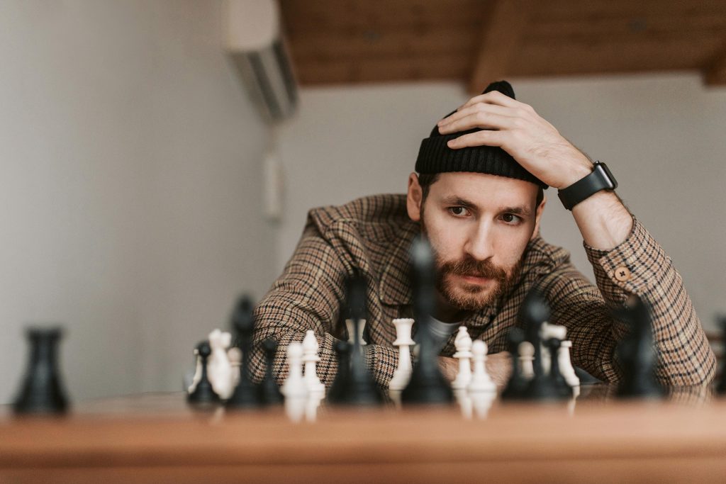 A man pondering about a chess field. This is the title image for an article on brand positioning, including plenty of brand positioning examples