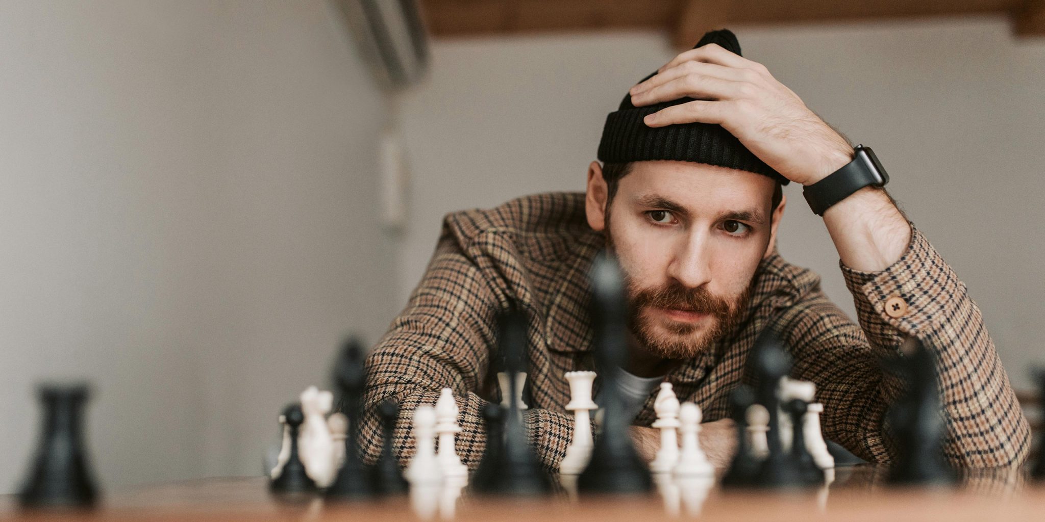 A man pondering about a chess field. This is the title image for an article on brand positioning, including plenty of brand positioning examples