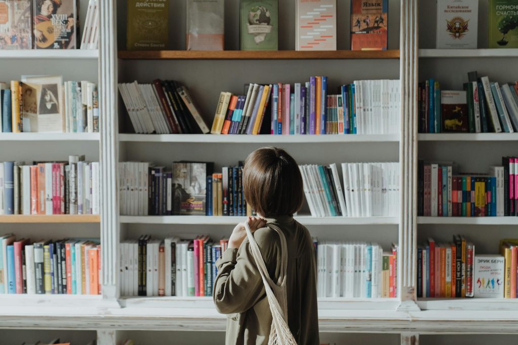 A woman browsing shelves in a book store as an introduction to the article "Boost Your Brand with Cialdini’s 6 Principles of Influence"