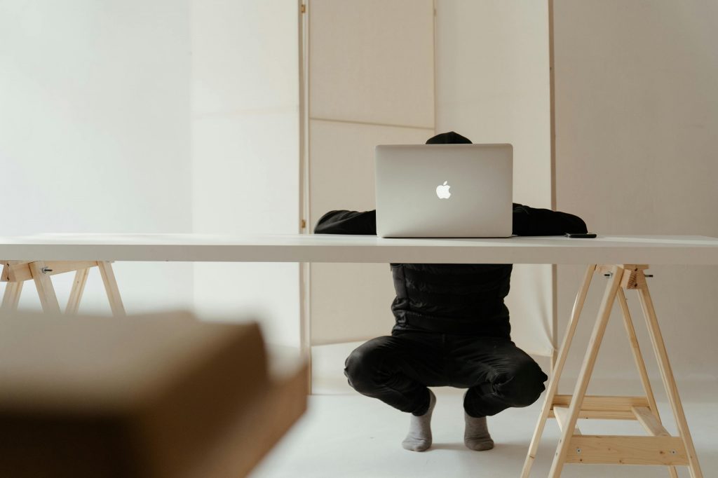 A man crouching behind a desk on a laptop as the intro image for the blog article "15 Reasons Why Your Brand Still Needs a Website in 2024"