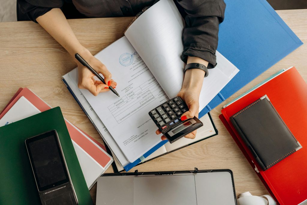 A close-up of hands reviewing documents at a desk, with folders and a calculator visible—setting the scene for an article about conducting a brand audit as a small business.