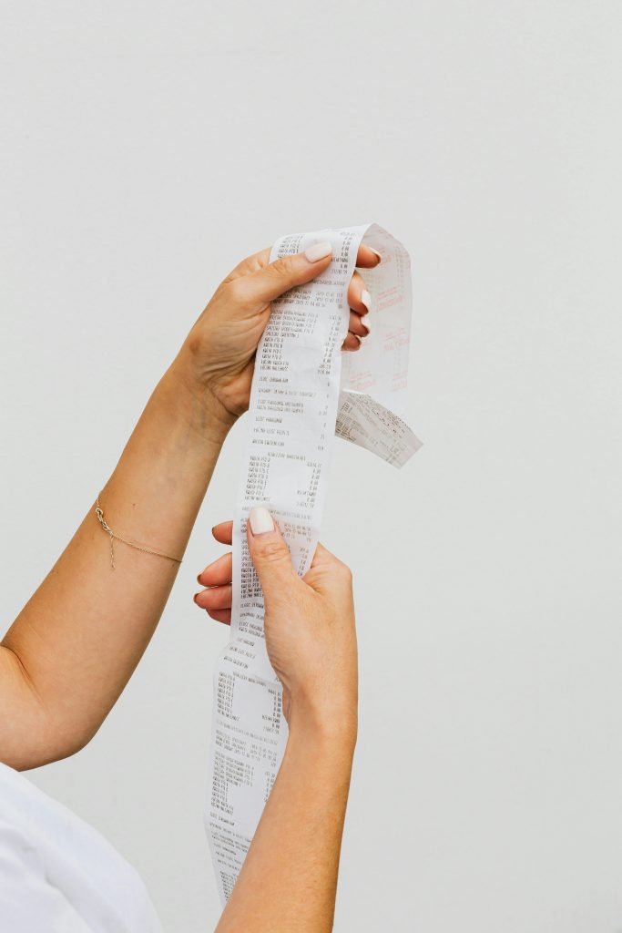 Hands holding a receipt against a plain white background. This is the introduction image for an article about the pricing and brand perception.